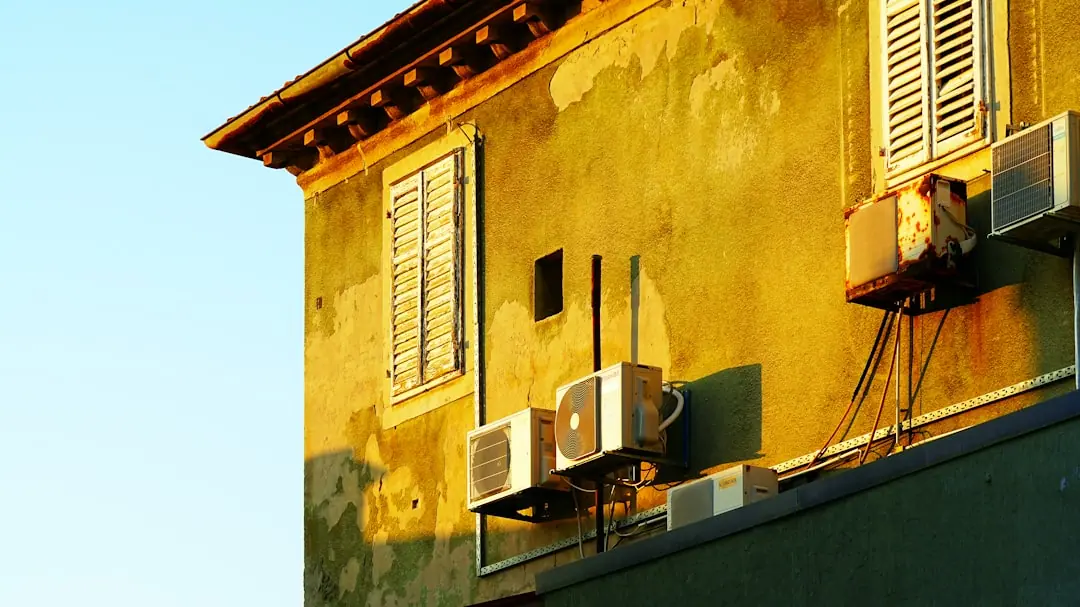 Sunlight illuminates an old building with air conditioners.